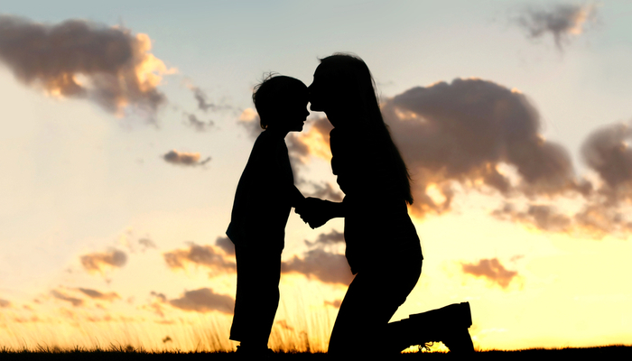 Silhouette of mother kissing her son on the head