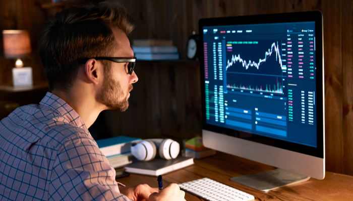 A man looking at graphs and data on a computer screen.