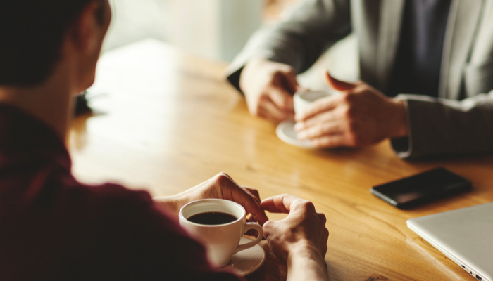 Two men talking over coffee in a café.