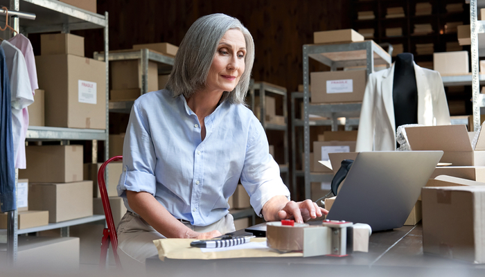 A woman working on a laptop in a warehouse.