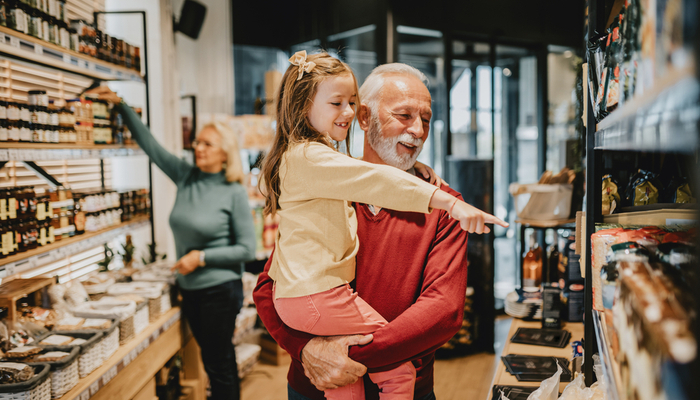 A grandfather grocery shopping with his granddaughter.