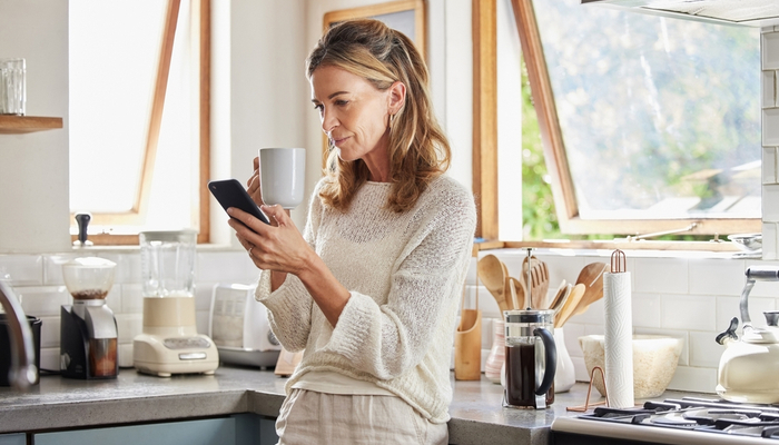 A woman drinking a coffee while looking at her phone.