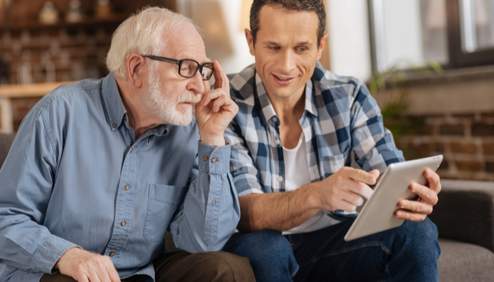 Young man showing his elderly father something on a tablet