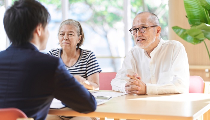 An older couple sits across a table from a younger man.