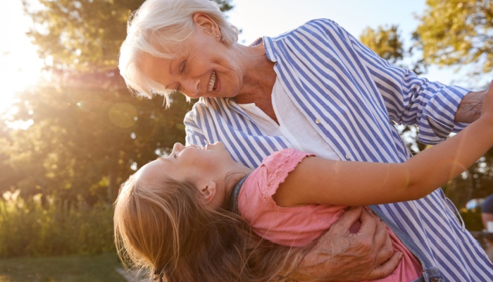 A grandmother playing with her granddaughter outside.